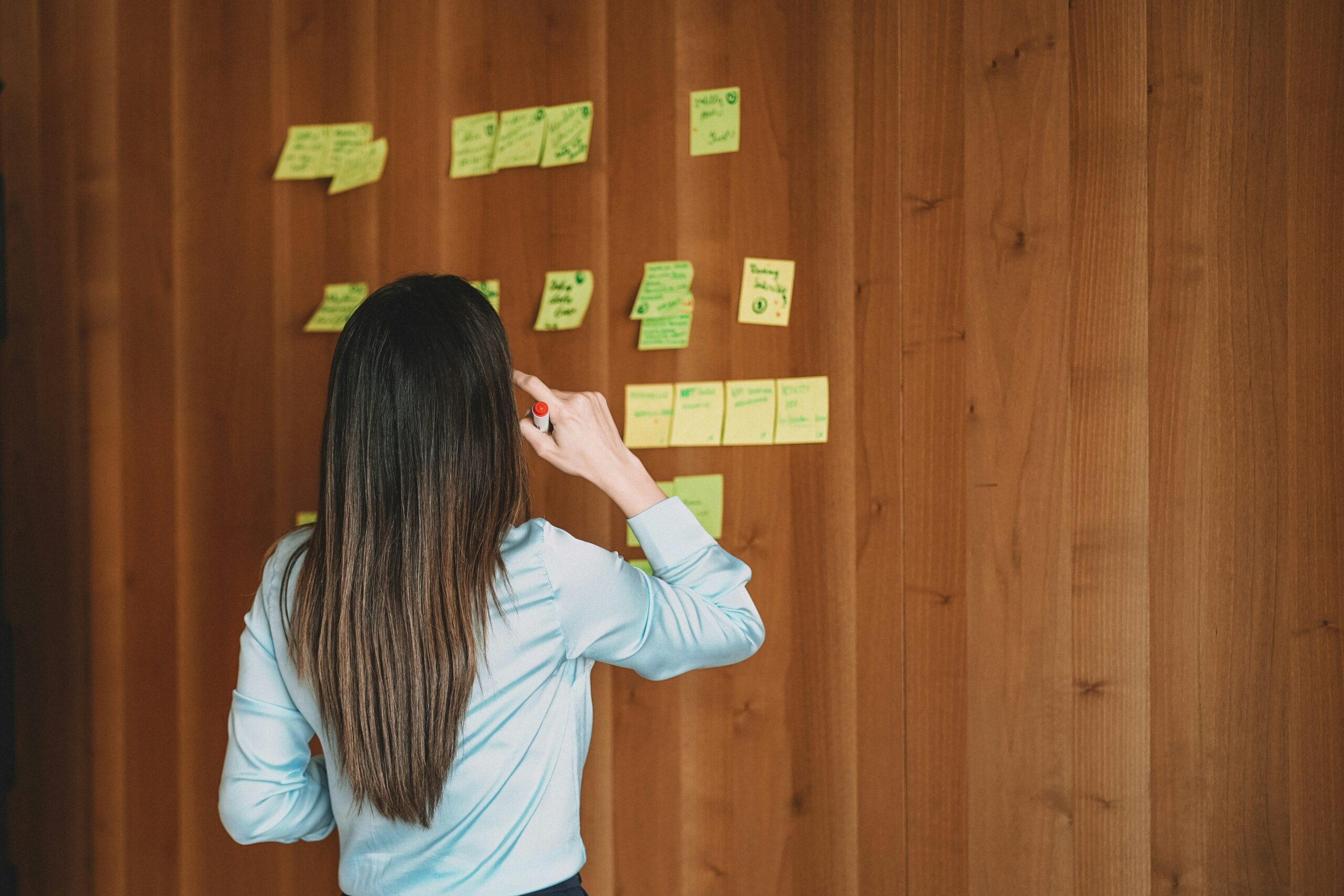 Eine Person steht vor einer Wand mit Sticky Notes.