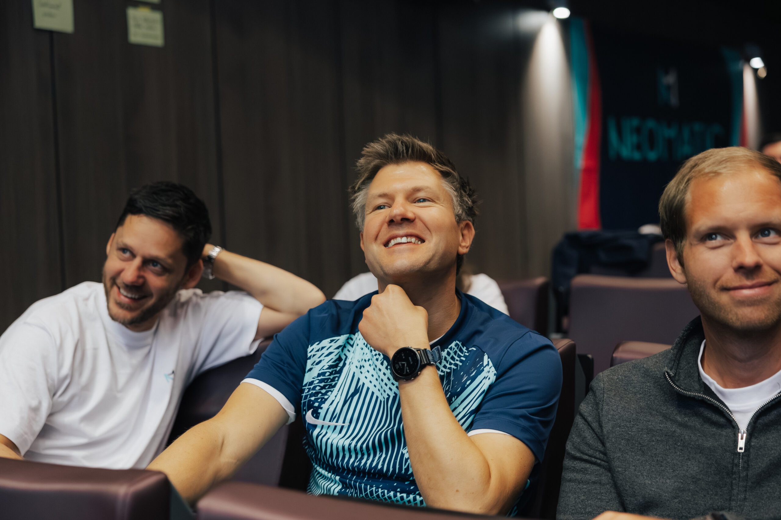 Drei Personen sitzen in einem Meetingraum und lachen